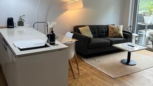 A modern kitchen with a central island, a dark sofa, and a small coffee table.
