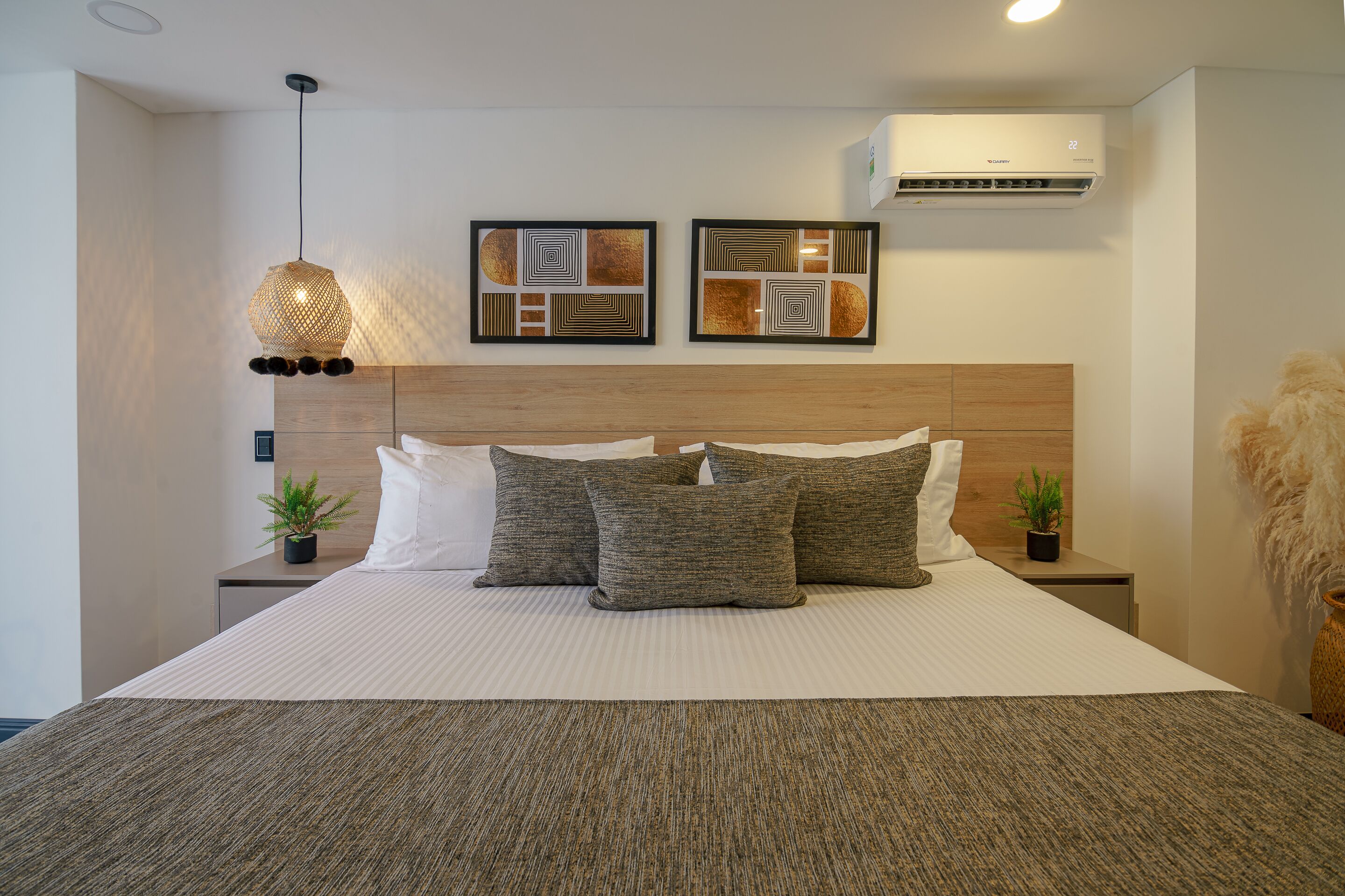 Ein modernes Schlafzimmer mit einem großen Bett, zwei Wandklimaanlagen und dekorativer Wandkunst.