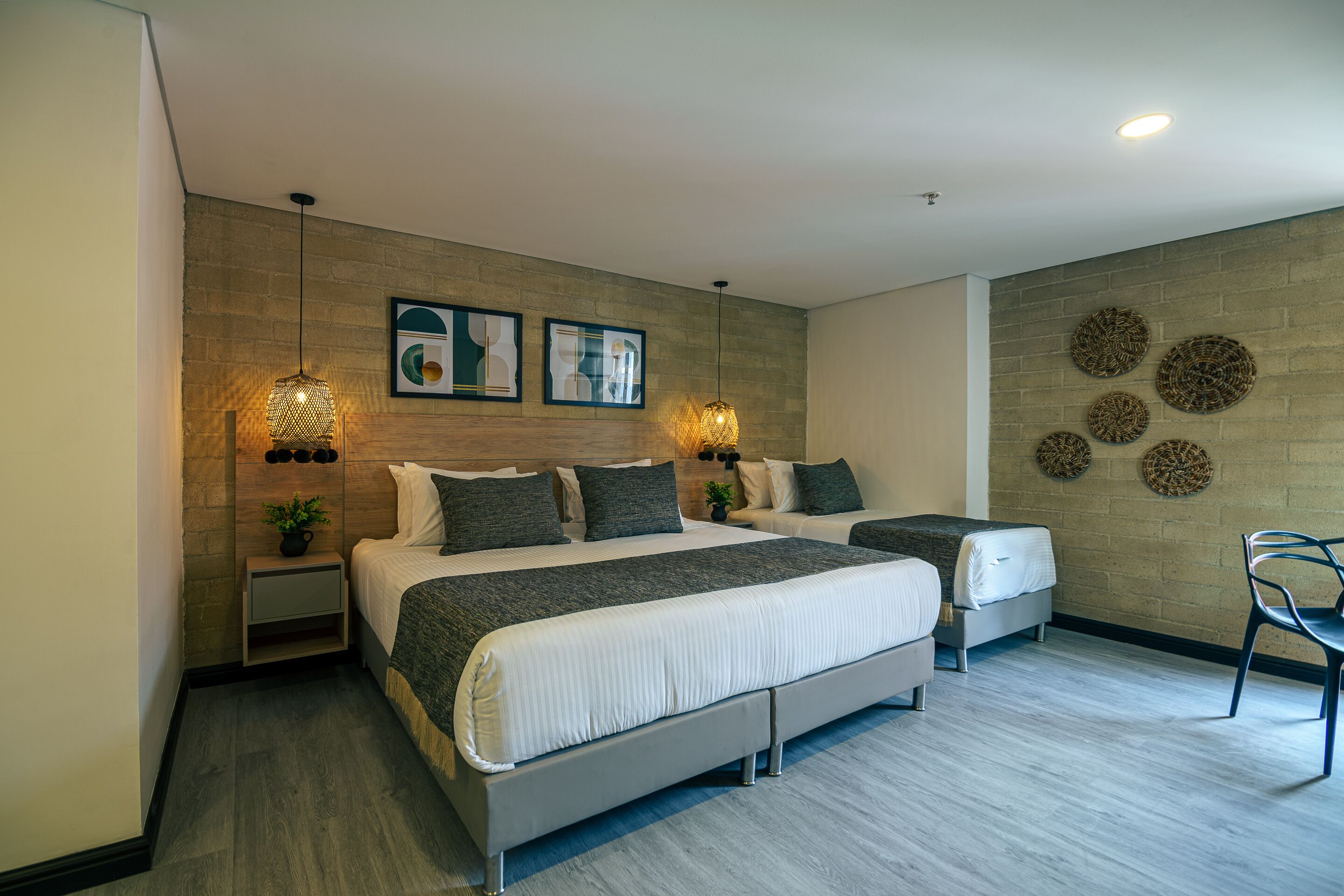 Een moderne slaapkamer met een groot bed, twee nachtkastjes, een stoel en decoratieve wandkunst.