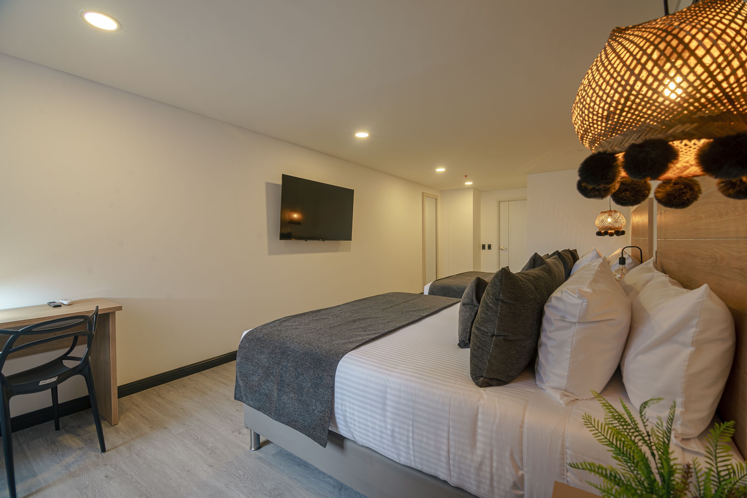 Une chambre avec un lit, un bureau et un téléviseur fixé au mur.