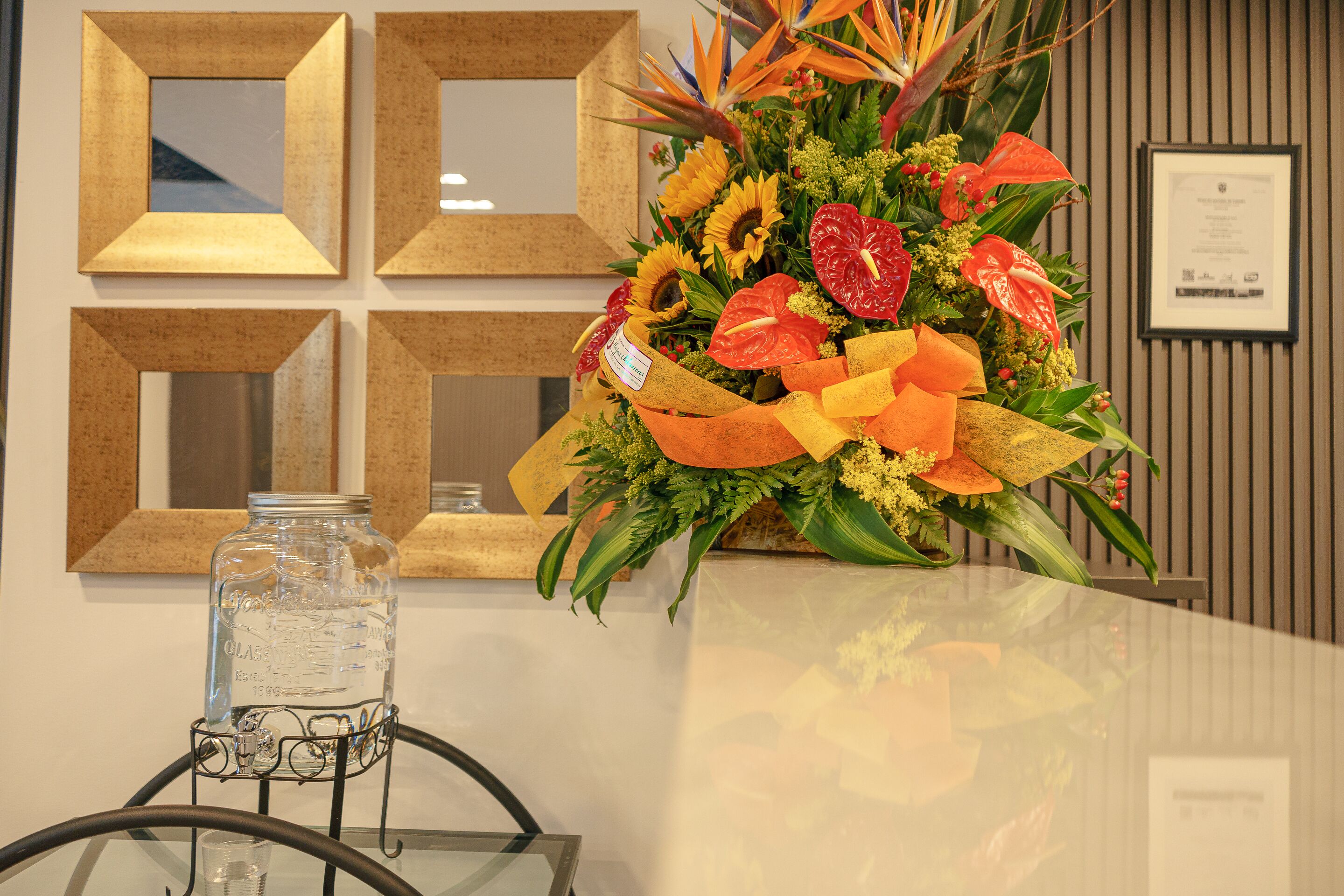 A reception area with a glass table, a water dispenser, and a floral arrangement.
