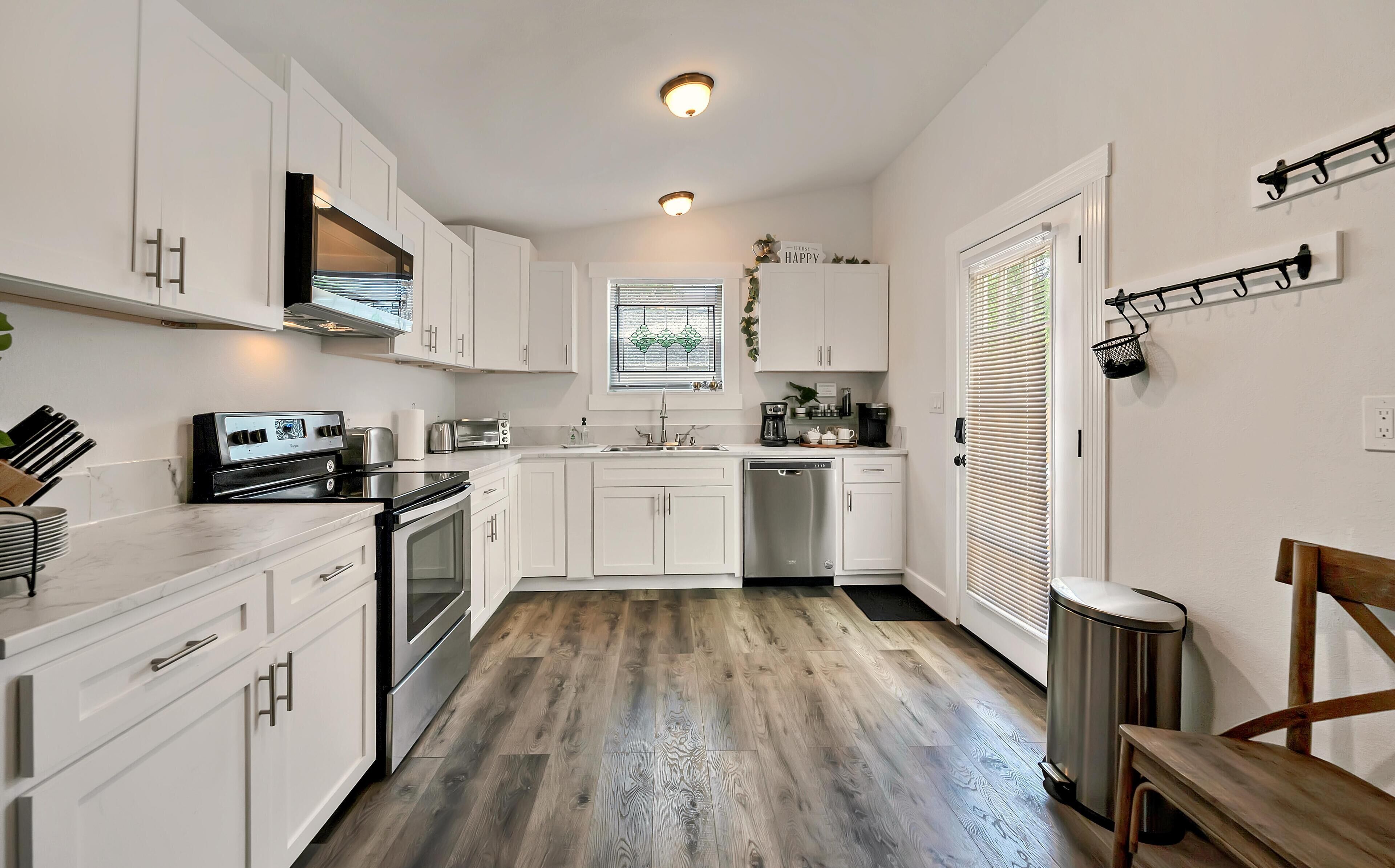 Una cocina moderna con armarios blancos, electrodomésticos de acero inoxidable y piso de madera.