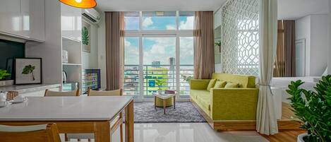 A modern living room with a dining area, a sofa, a coffee table, and a large window with a city view.