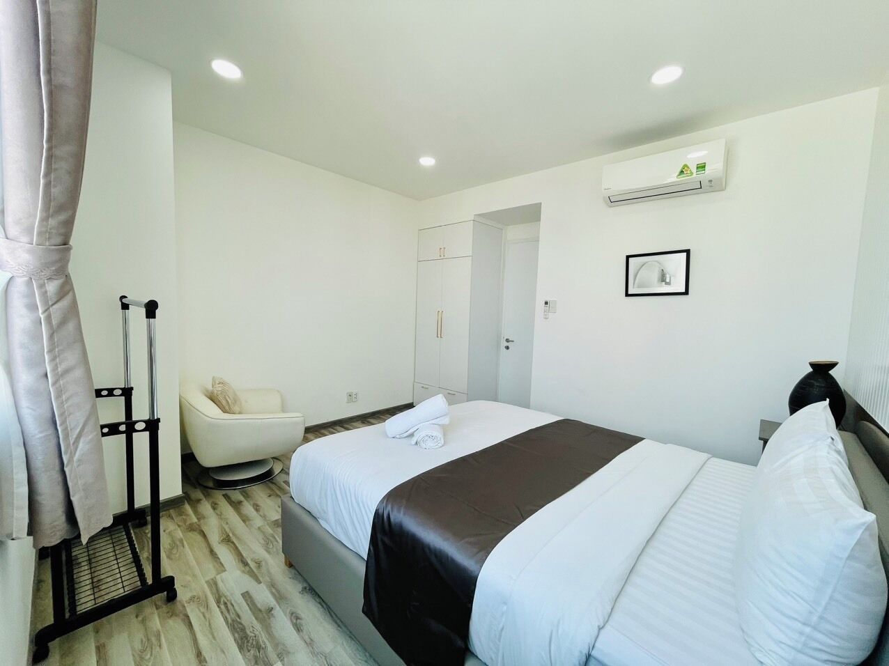 Habitación de hotel con cama, una silla, armario y aire acondicionado.