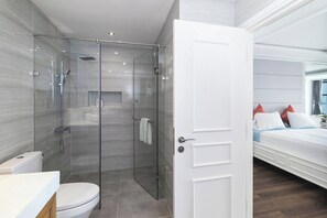 A modern bathroom with a glass-enclosed shower, a toilet, and a sink.