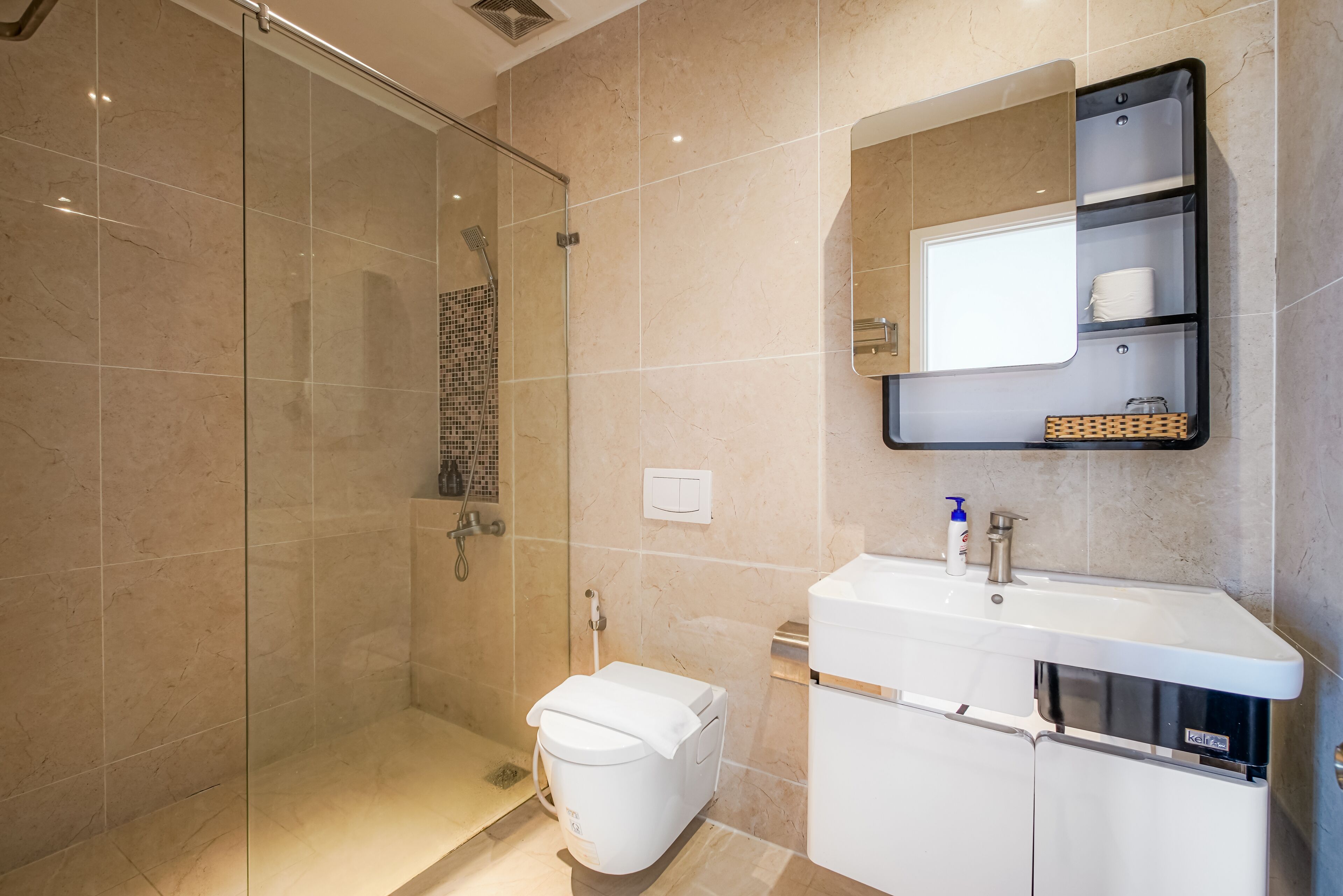 Un baño moderno con cabina de ducha de vidrio, inodoro blanco y lavabo con espejo.