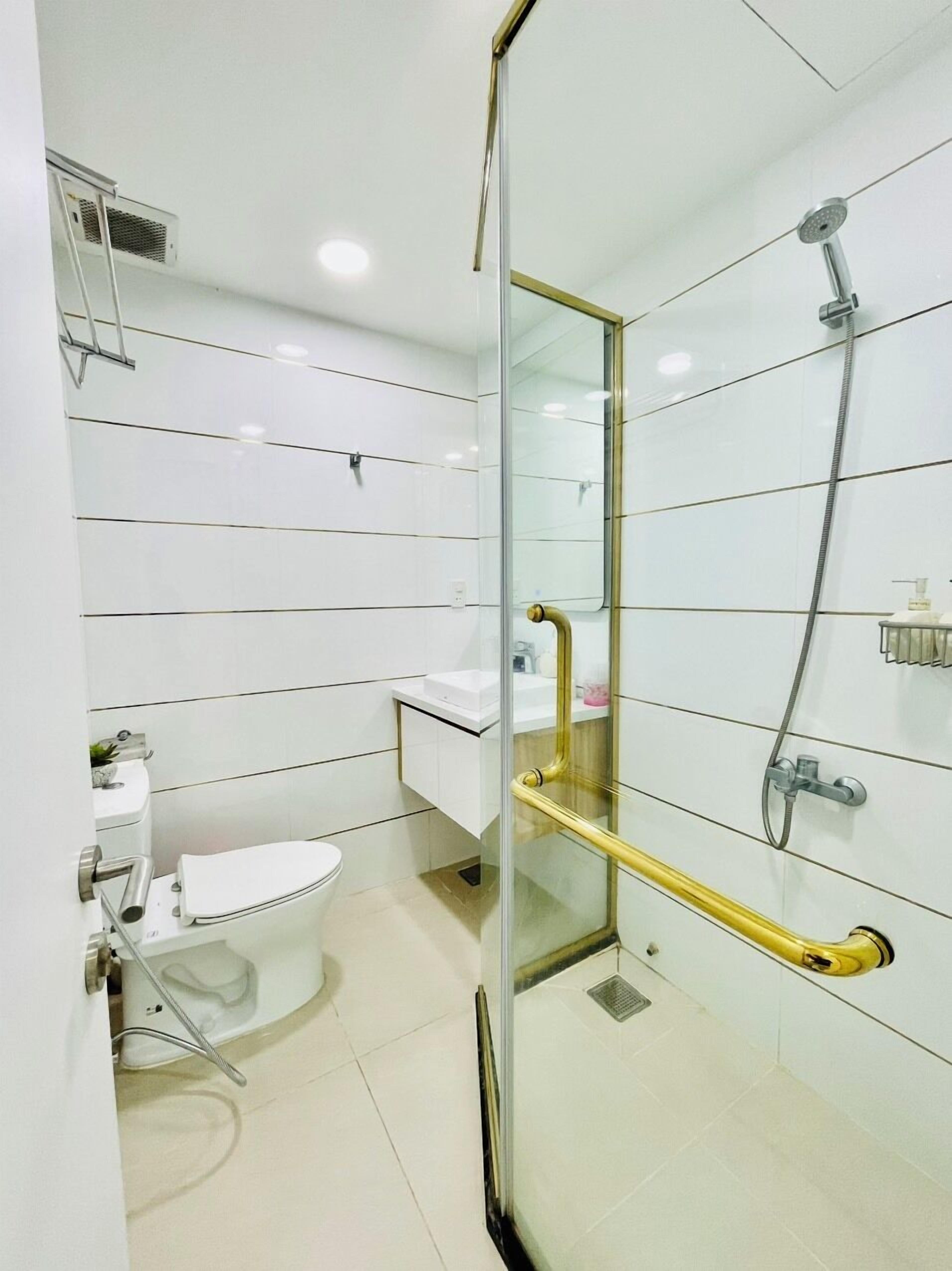 Un baño moderno con cabina de ducha de vidrio, inodoro blanco y lavamanos con espejo.