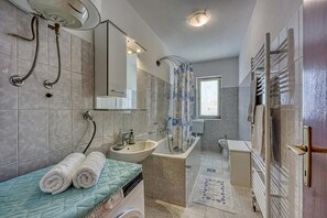 A modern bathroom with a sink, mirror, shower, and towel rack.