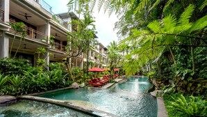 A hotel with a pool surrounded by lush greenery and red umbrellas. - AnandaDara Ubud Resort & Spa (Ubud)