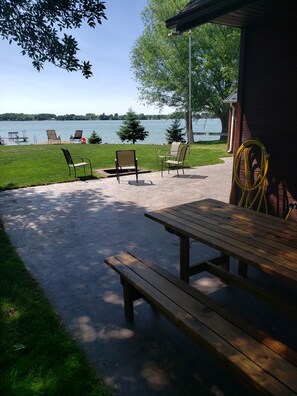 A picnic area with a wooden table and chairs, a hose, and a view of a lake.