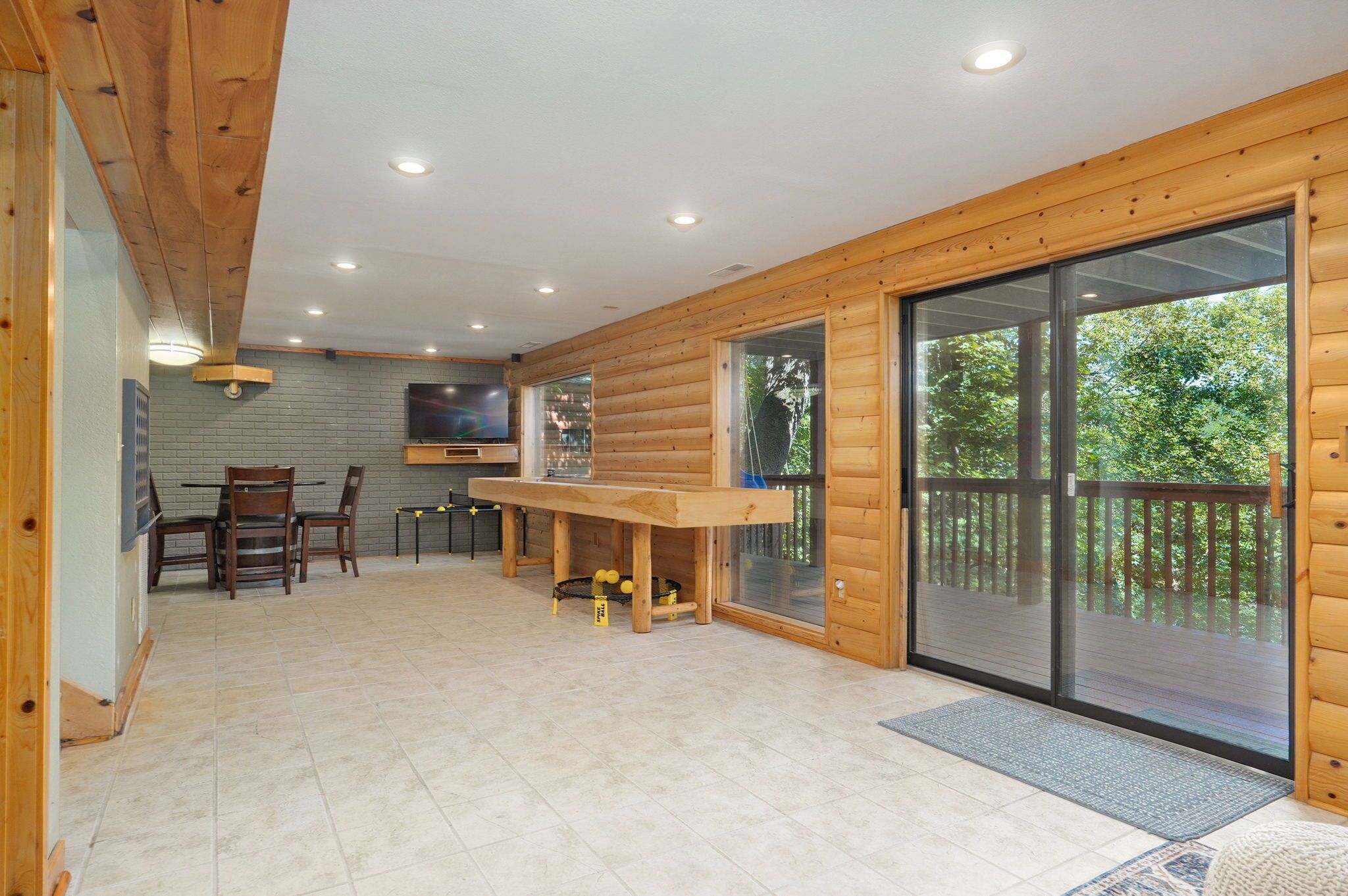A log cabin interior with a dining area, a kitchen, and a sliding glass door leading to a deck.