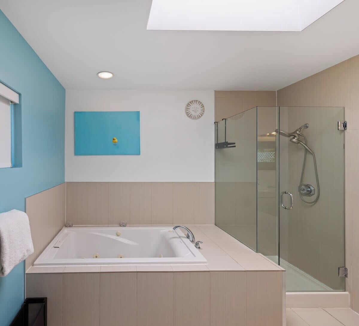 Une salle de bain moderne avec une douche à parois de verre, une baignoire sur pieds et un mur d’accent bleu.