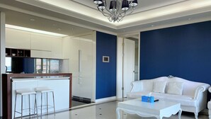 Una sala moderna con un sofá blanco, una mesa de centro blanca y una zona de bar con taburetes.