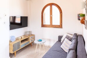 A modern living room with a flat-screen TV, a wooden cabinet, a small round table, a sofa, and a window with an arched design. - Bental's Dream Place With Lake And Sea View (Kavallos)