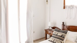 A hotel room with a bed, a nightstand, a lamp, and a window with curtains. - Bental's Dream Place With Lake And Sea View (Kavallos)