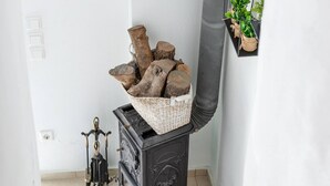A staircase leading to a room with a black dresser, a basket of firewood, and a small potted plant on the wall. - Bental's Dream Place With Lake And Sea View (Kavallos)