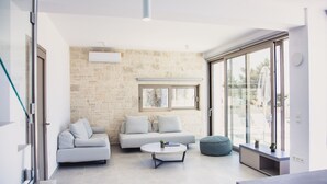 Un salon moderne avec un mur en pierre, un canapé, une table basse et une porte vitrée donnant sur l’extérieur.