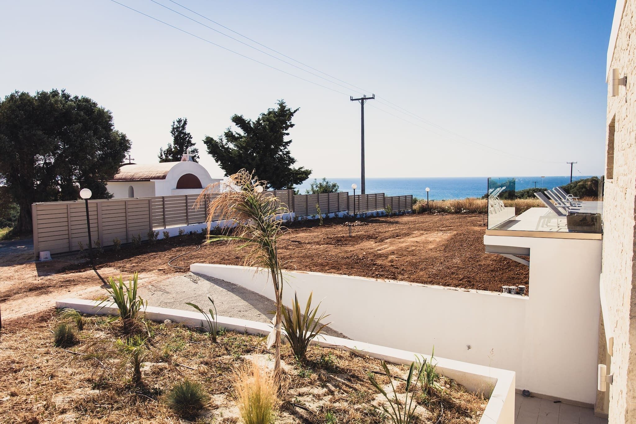 A coastal property with a paved driveway, a white building with a modern design, and a view of the sea.