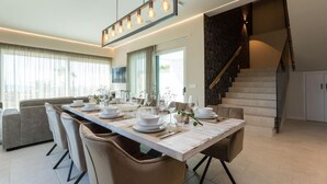 A modern dining area with a long table set for a meal, a staircase, and a view of the outdoors. - Villa Four Seasons Ljubac Seaside (Ražanac)