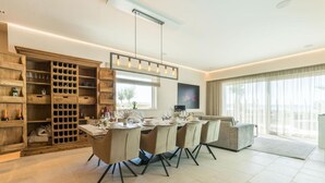 A modern dining area with a long table, chairs, and a wooden wine rack. - Villa Four Seasons Ljubac Seaside (Ražanac)