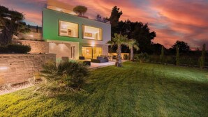 A modern two-story house with a green facade, a stone retaining wall, and a well-maintained lawn. - Villa Four Seasons Ljubac Seaside (Ražanac)