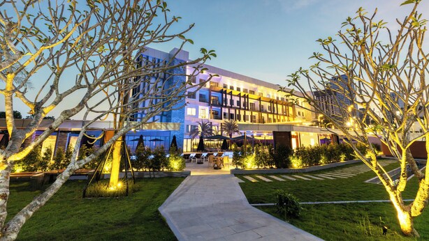 A modern hotel with a well-lit outdoor area, including a pool and lounge chairs. - Munich Hotel (Sihanoukville)