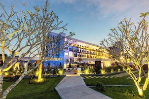 A modern hotel with a well-lit outdoor area, including a pool and lounge chairs.