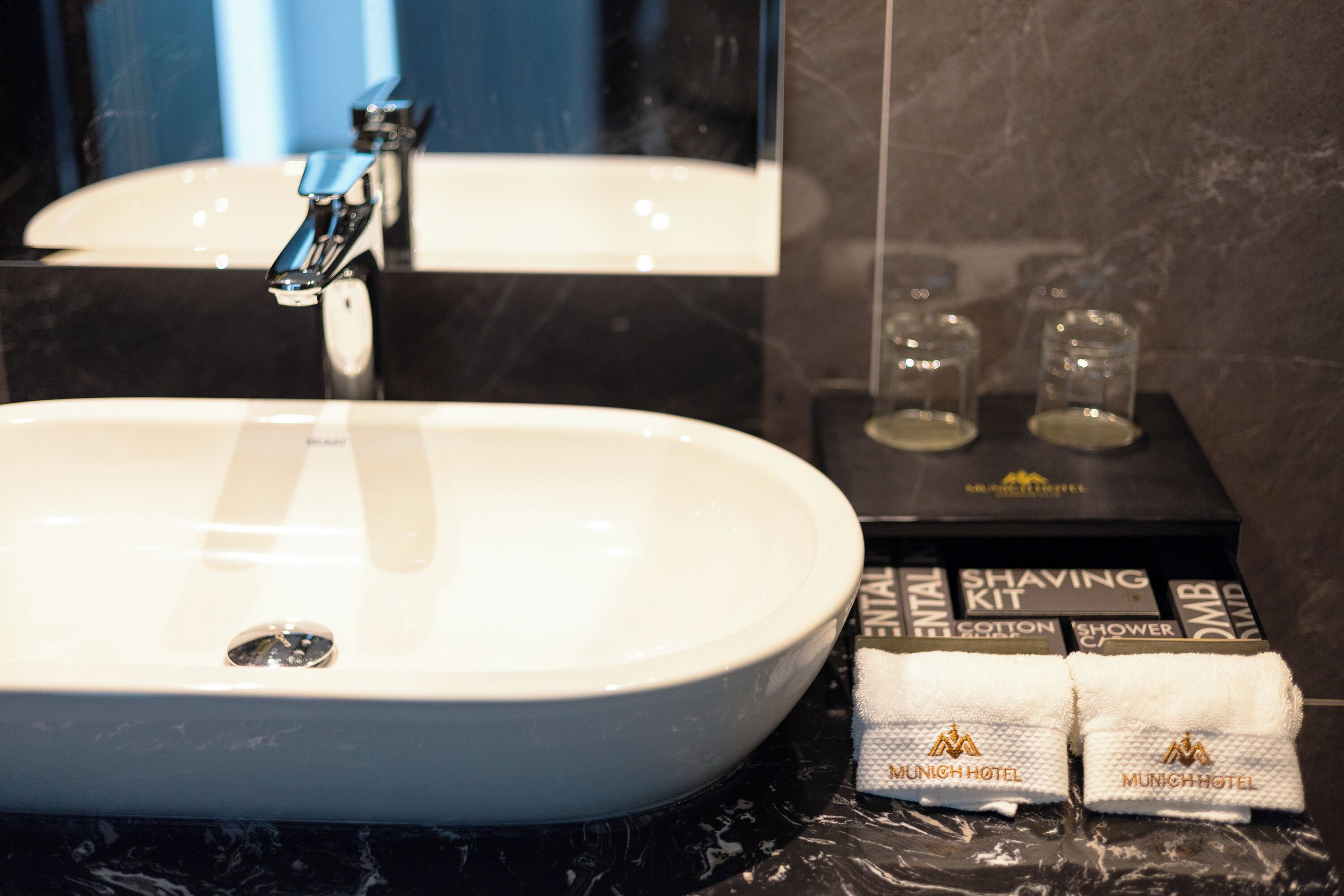 Un baño con un lavabo blanco, un espejo y un kit de afeitado en la encimera.