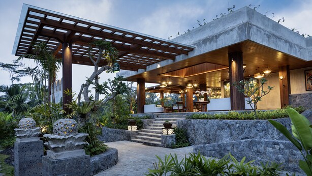 A modern outdoor patio area with a pergola, stone steps, and lush greenery. - Inara Alas Harum (Payangan)