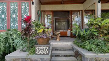 Una escalera de piedra conduce a una puerta de madera, rodeada de exuberante vegetación tropical.