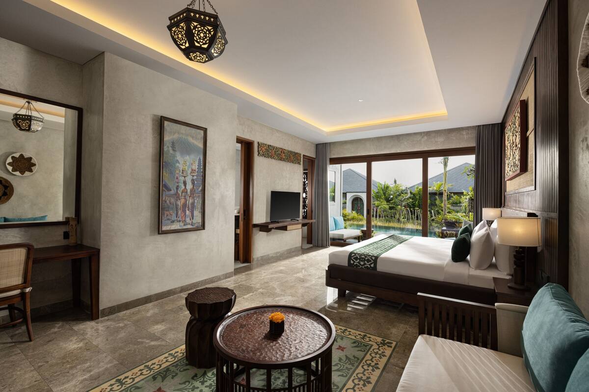 A hotel room with a large bed, a desk, a chair, a small round table, and a television.