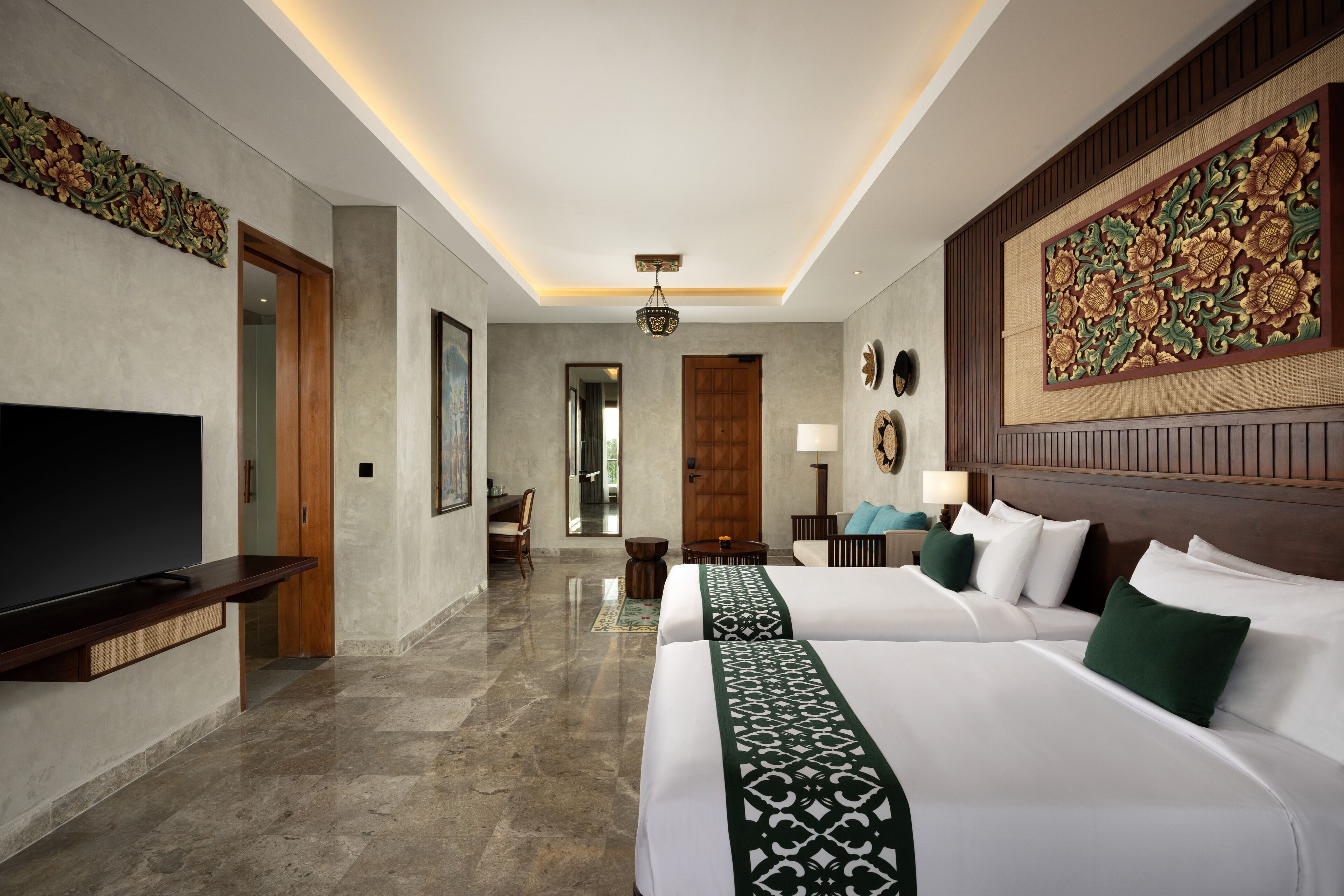A hotel room with two beds, a TV, a wooden door, and a large decorative wall panel.