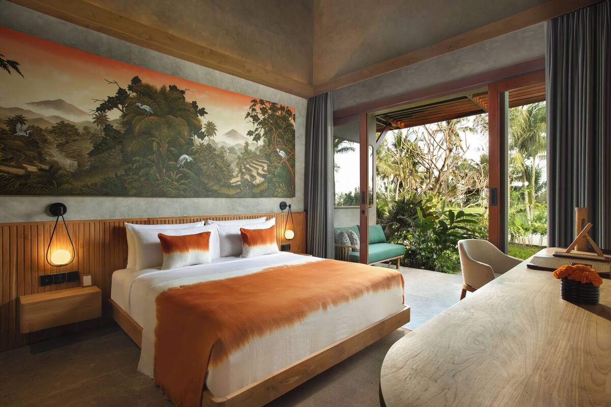 A spacious bedroom with a large bed, a desk, and a view of the outdoors.