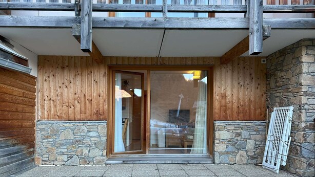 A wooden exterior with a stone foundation, a glass door entrance, and a metal railing. - Studio Résidence LE Parc DES Airelles (LES ORRES 1800)