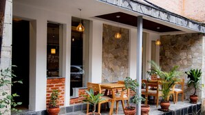 A covered outdoor seating area with stone walls, wooden furniture, and potted plants. - Vastu Boutique Hotel (Kathmandu)