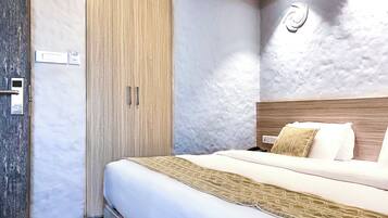 A hotel room with a bed, a wardrobe, and a wall-mounted light fixture.