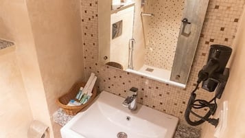 Un baño con lavamanos blanco, un espejo, un perchero para toallas y un secador de pelo.