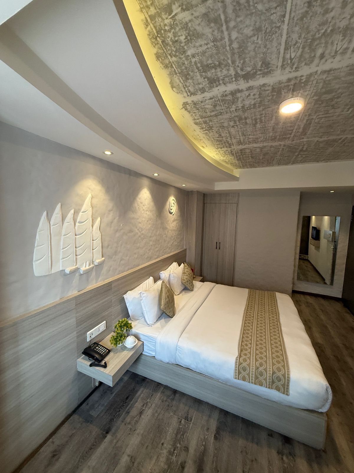 Un dormitorio moderno con una cama grande, una mesita de noche con lámpara y un aplique en la pared.