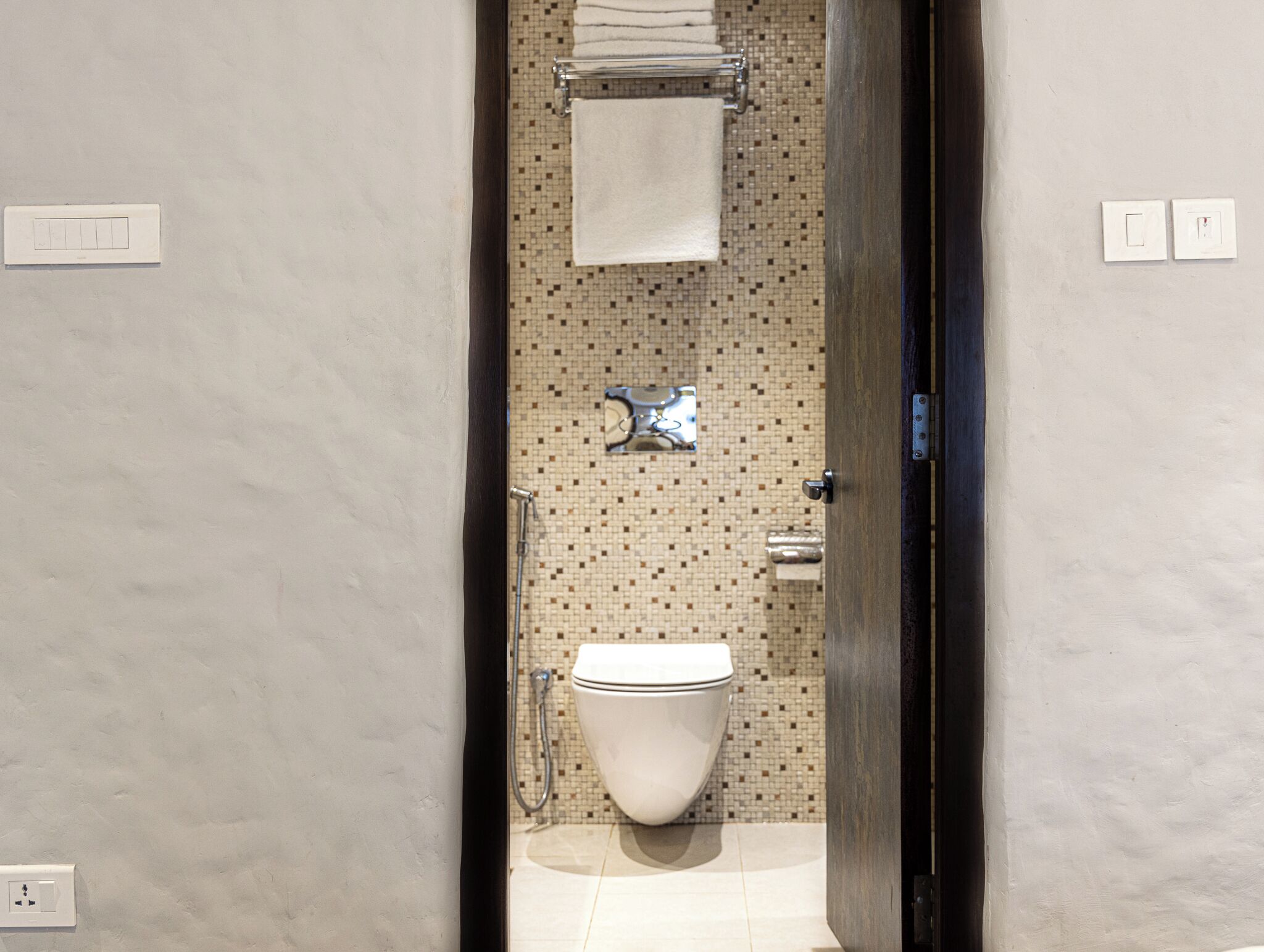 A bathroom with a toilet, a towel rack, and a shower.