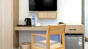 A compact kitchenette with a wooden chair, a television, and a refrigerator. - Vastu Boutique Hotel (Kathmandu)