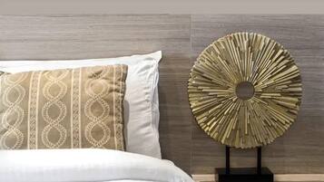 A neatly made bed with a patterned pillow and a decorative wall piece.