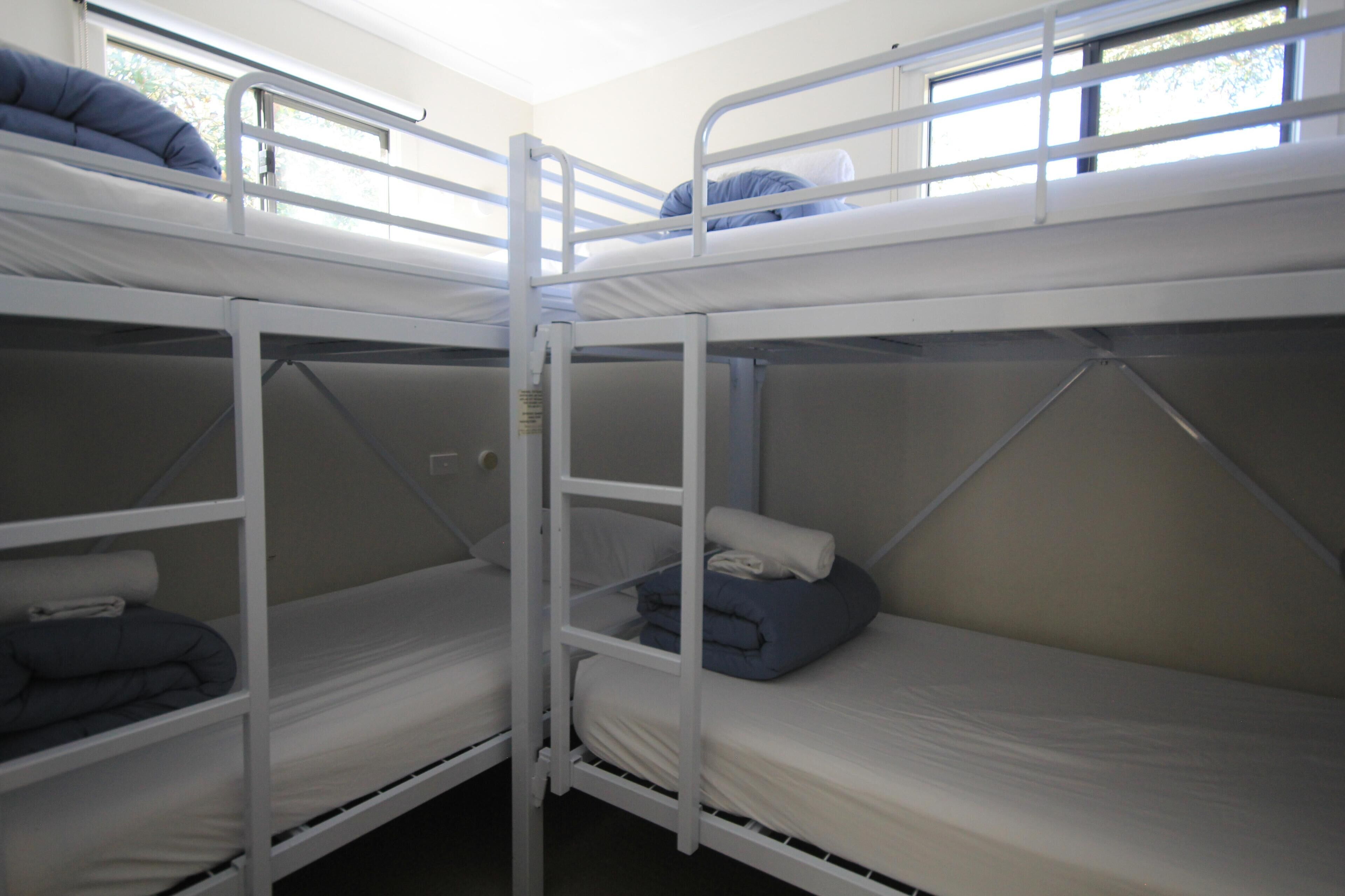 A bunk bed room with two beds, each with pillows and blankets.