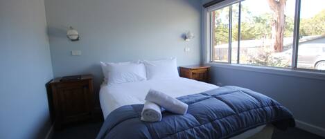 A bedroom with a bed, a window, and a nightstand.