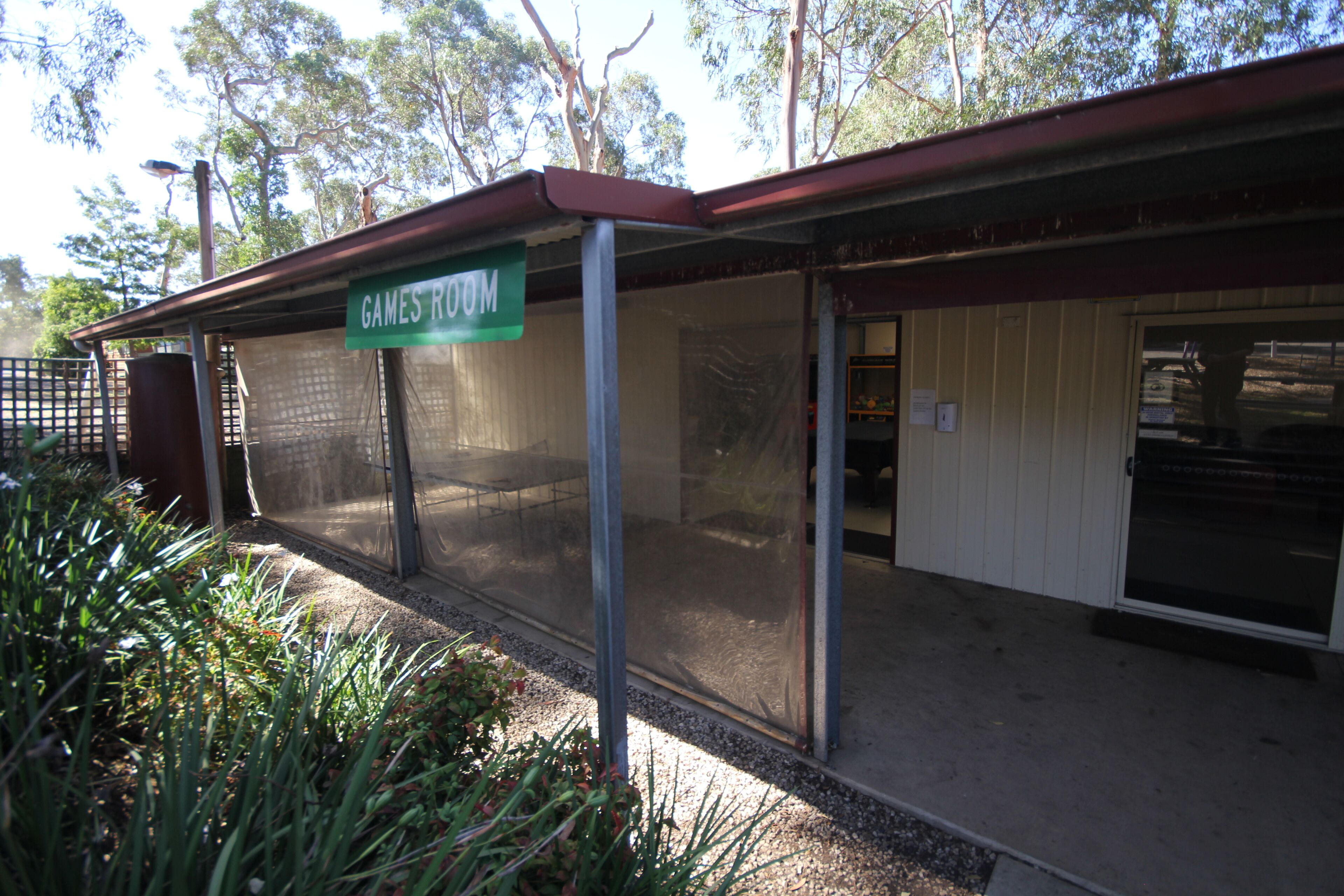 A building with a sign reading "GAMES ROOM" and a covered outdoor area.
