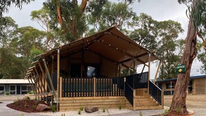 Een houten chalet met een balkon, een trap en een bordje met daarop 'kantoor'.