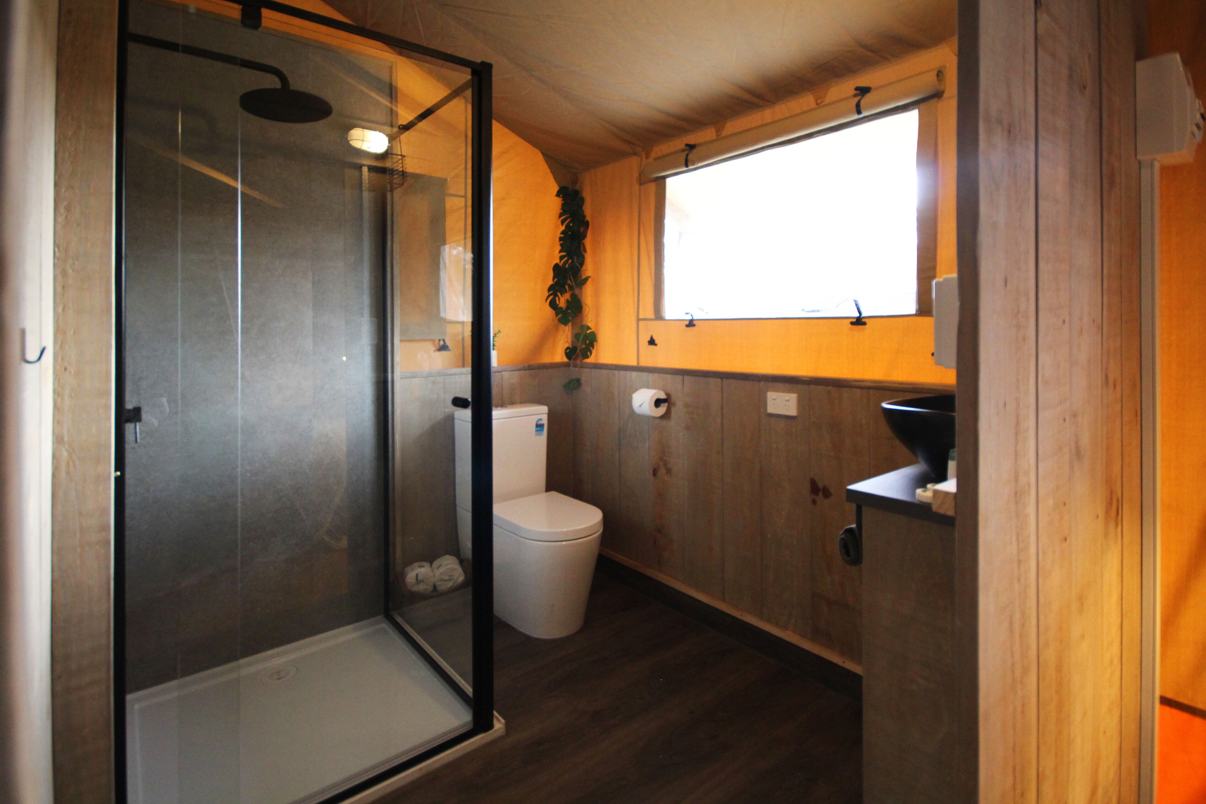 A compact bathroom with a glass shower enclosure, a toilet, and a sink.