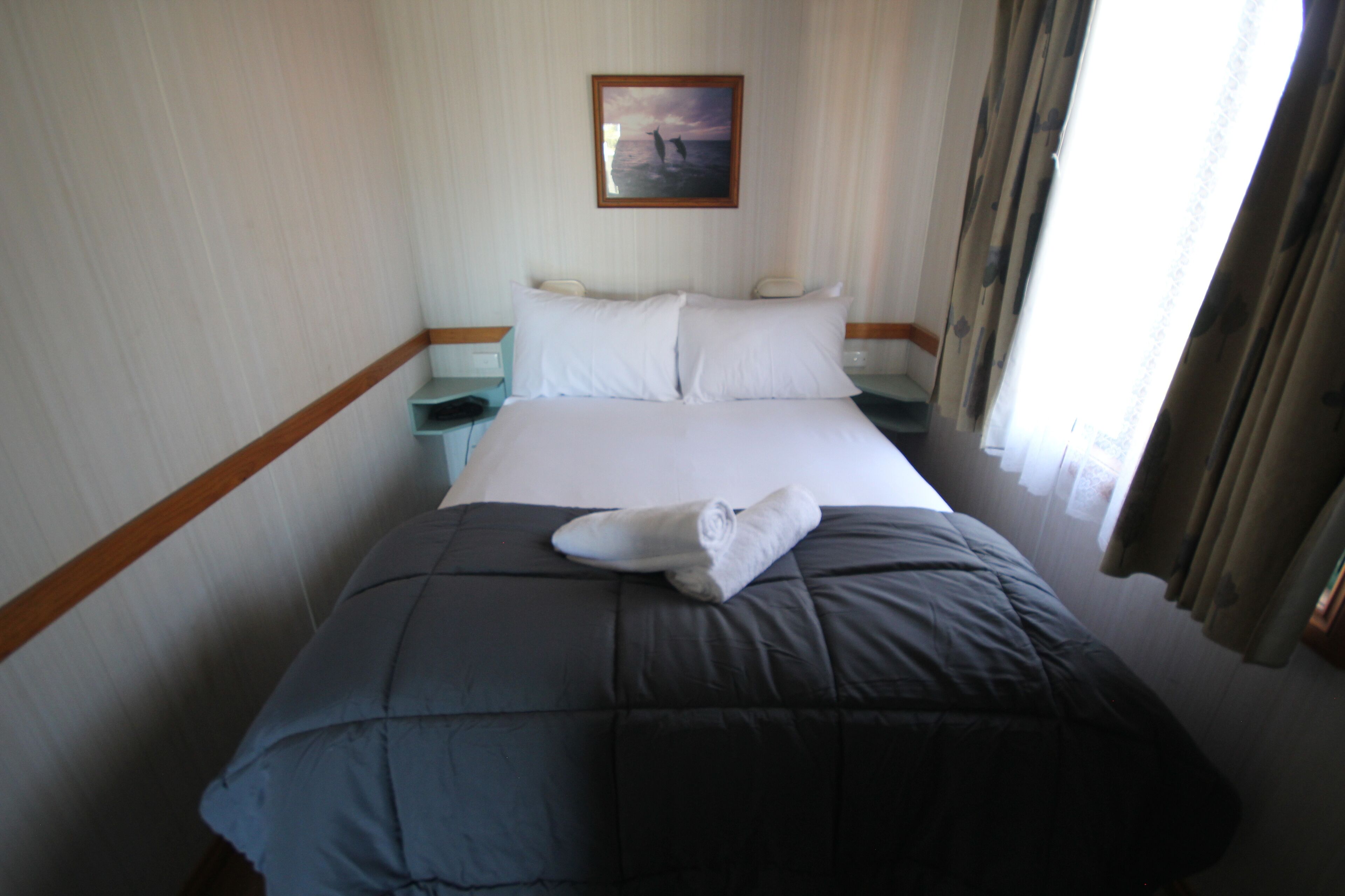 Ein Hotelzimmer mit Bett, Nachttisch, Lampe und einem Bild an der Wand.