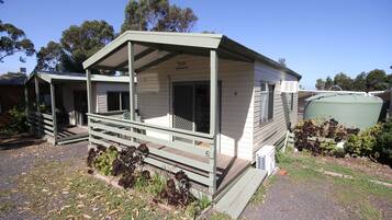 A single-story mobile home with a porch, a small garden area, and a water tank in the backyard.
