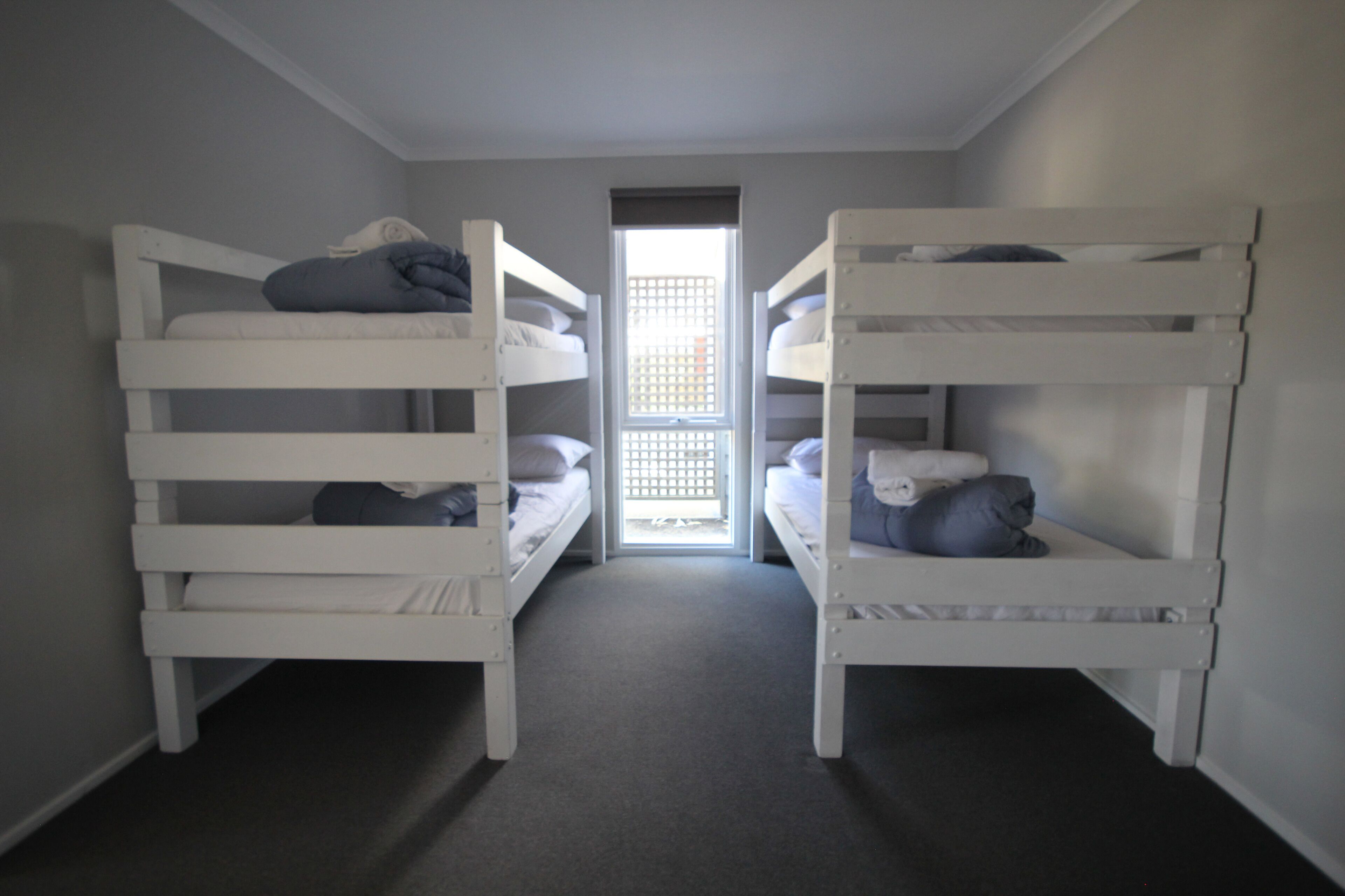 Ein Zimmer mit zwei Etagenbetten, einem kleinen Fenster und Teppichboden.