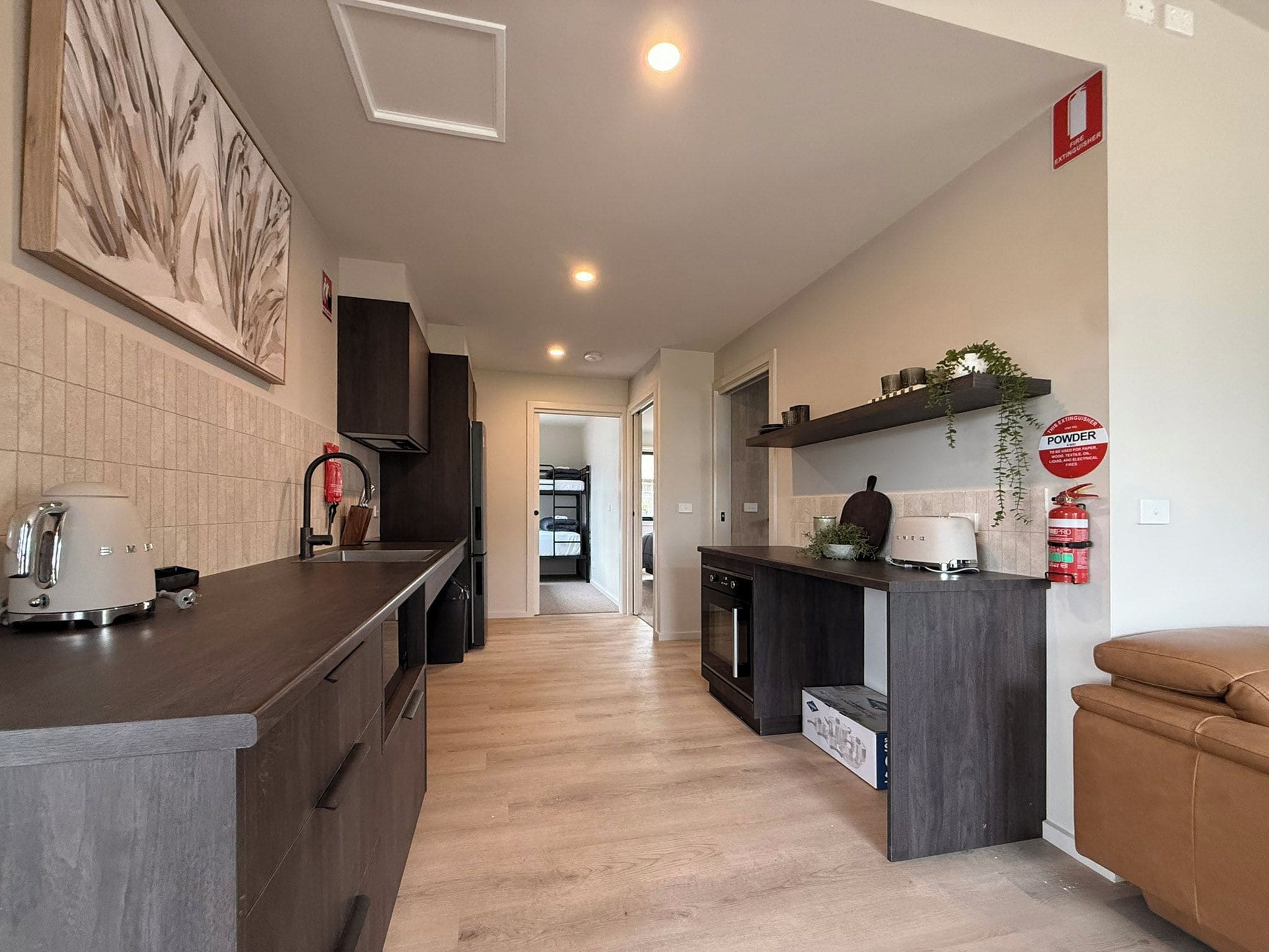 Cozinha moderna com ilha central, armários escuros e vista para o quarto adjacente.